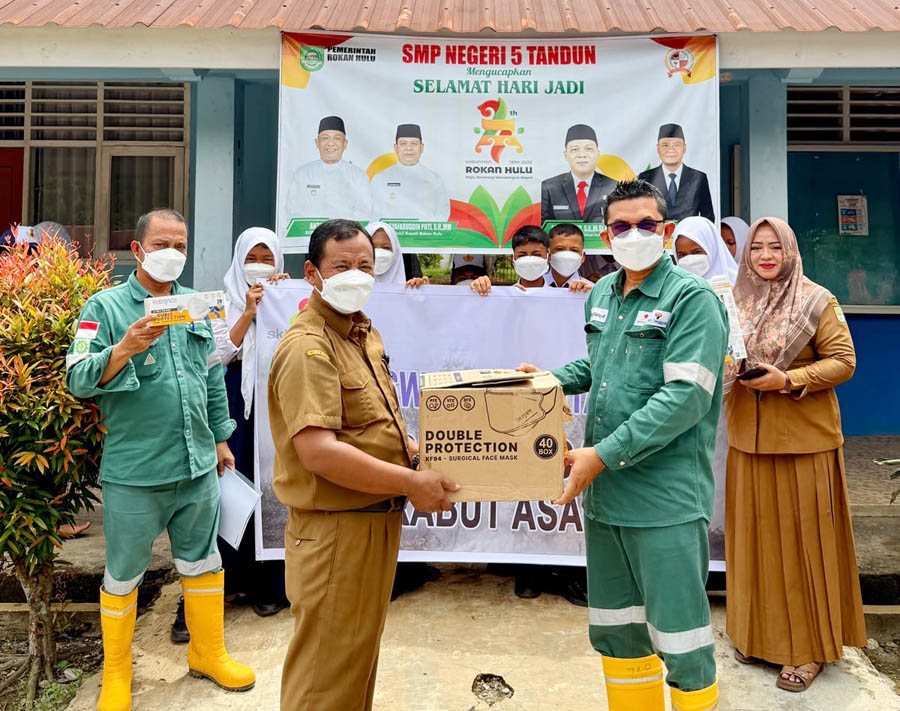 Rafiq Adriansyah selaku Head of Field Support dan Supriadi selaku Public & Government Relation Kingswood Capital Ltd. Menyerahkan masker kepada Irianto selaku Kepala Sekolah SMPN 5 Tandun